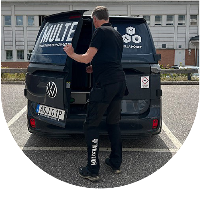 Multeral-anställd i uniform öppnar bakluckan på en svart bil med Multeral-logga